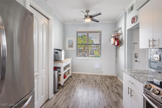 kitchen with crown molding, appliances with stainless steel finishes, light hardwood / wood-style floors, light stone counters, and white cabinetry