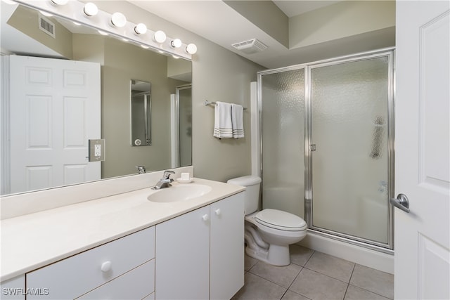 bathroom featuring toilet, vanity, tile patterned floors, and an enclosed shower