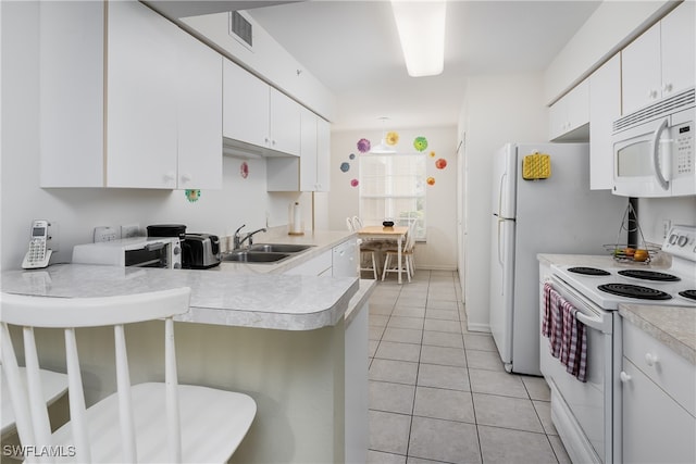 kitchen featuring kitchen peninsula, white appliances, sink, white cabinetry, and light tile patterned flooring