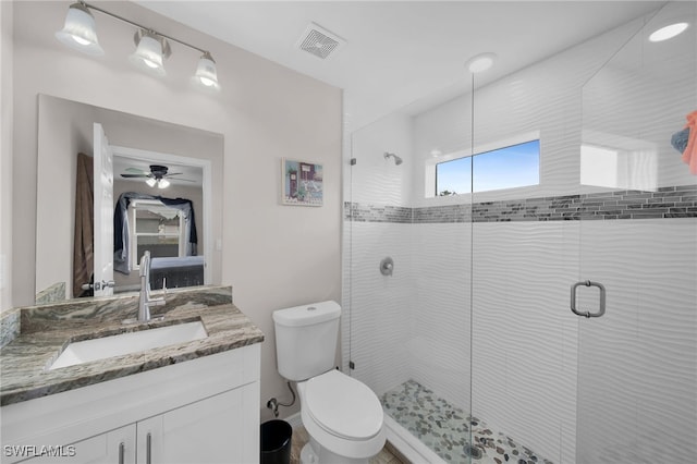 bathroom with ceiling fan, toilet, a shower with door, and vanity