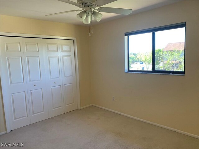 unfurnished bedroom featuring ceiling fan, light colored carpet, and a closet