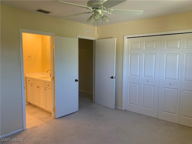 unfurnished bedroom featuring light colored carpet, ceiling fan, sink, connected bathroom, and a closet