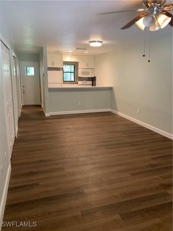 unfurnished living room with ceiling fan and dark wood-type flooring