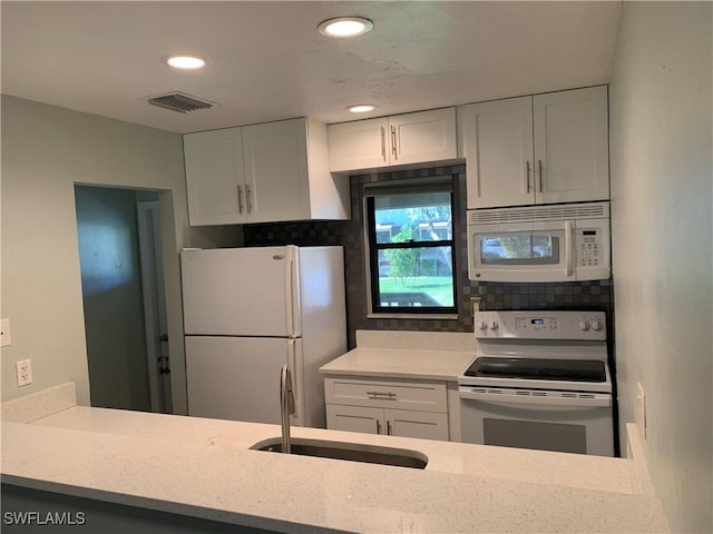 kitchen featuring backsplash, light stone counters, white appliances, sink, and white cabinetry