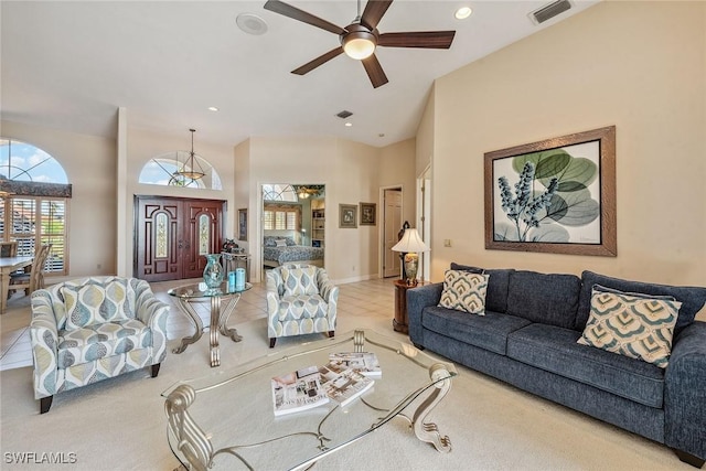 living area with high vaulted ceiling, visible vents, and a ceiling fan