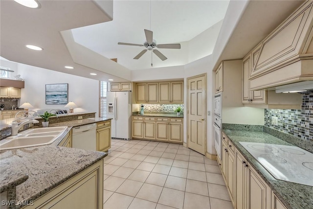 kitchen featuring white appliances, stone countertops, ceiling fan, a sink, and backsplash