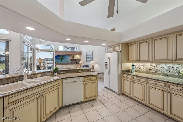 kitchen featuring decorative backsplash, open floor plan, a sink, ceiling fan, and white appliances