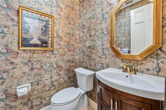 bathroom with visible vents, vanity, toilet, and wallpapered walls