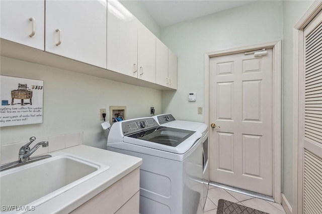 washroom with light tile patterned floors, a sink, cabinet space, and washer and dryer