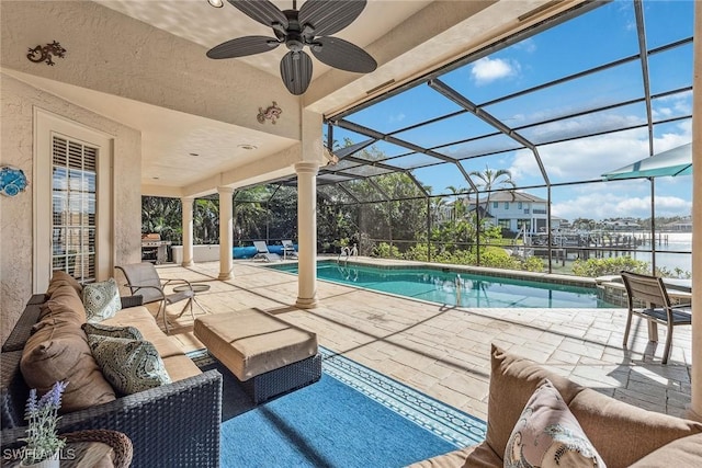 pool featuring a water view, a patio area, glass enclosure, ceiling fan, and an outdoor living space