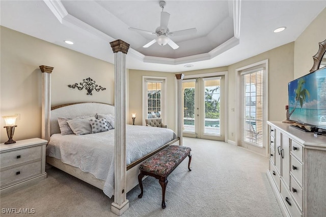 bedroom with light carpet, ornamental molding, access to exterior, a tray ceiling, and ornate columns