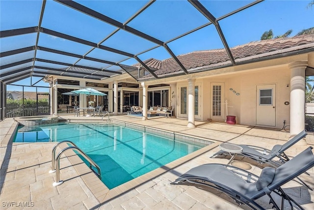 view of swimming pool featuring a pool with connected hot tub, a lanai, and a patio