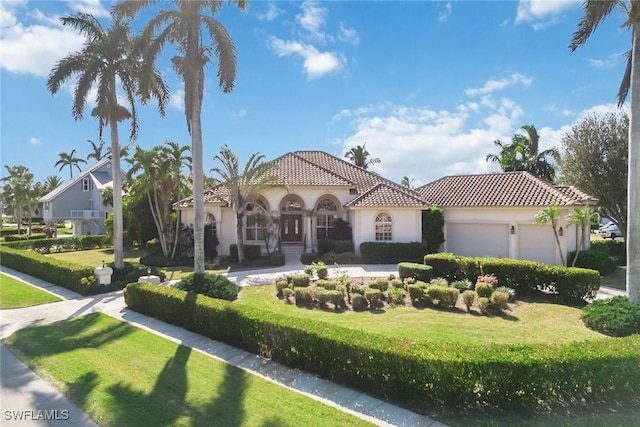 mediterranean / spanish-style house with a garage, a front yard, a tile roof, and stucco siding