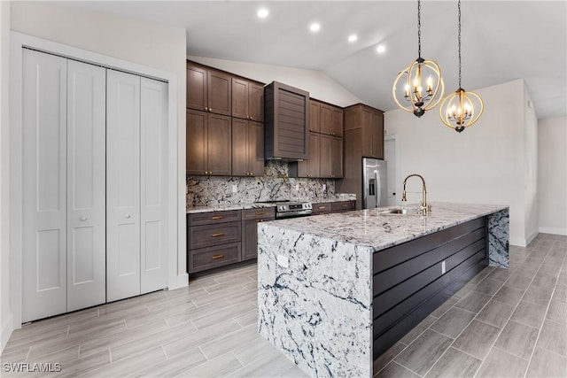 kitchen featuring decorative light fixtures, lofted ceiling, sink, a kitchen island with sink, and stainless steel appliances