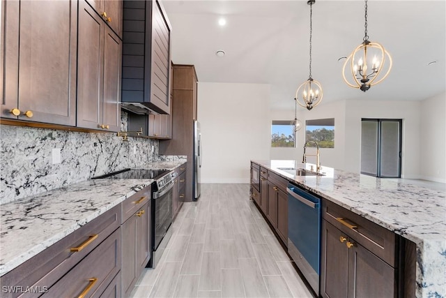 kitchen featuring appliances with stainless steel finishes, pendant lighting, sink, backsplash, and light stone countertops