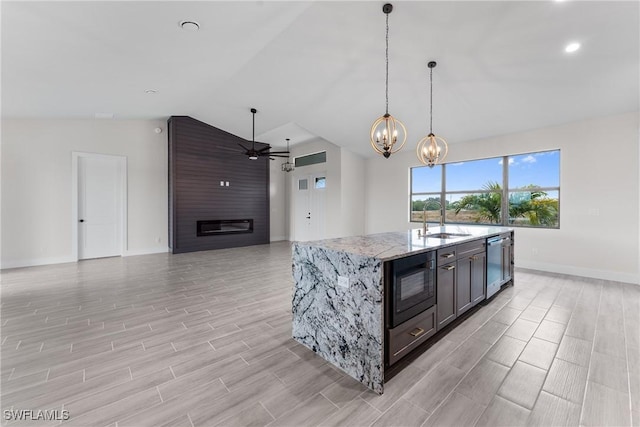 kitchen featuring lofted ceiling, sink, dishwasher, black microwave, and light stone countertops