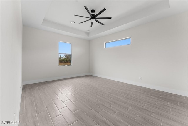 spare room with a tray ceiling and ceiling fan