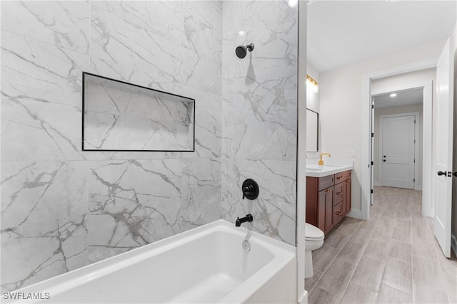 full bathroom featuring tiled shower / bath, vanity, and toilet