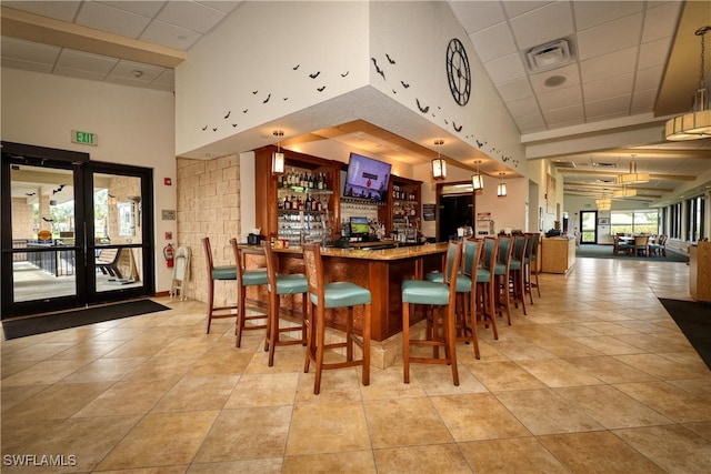 bar featuring a towering ceiling, pendant lighting, and light tile patterned floors