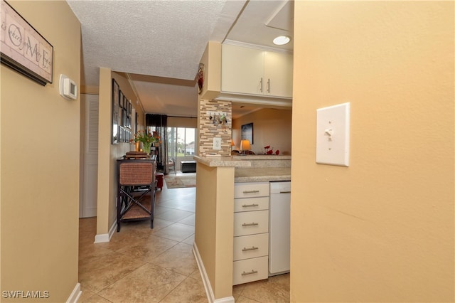 kitchen featuring kitchen peninsula, dishwasher, light tile patterned floors, and a textured ceiling