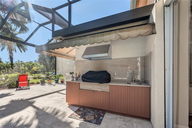 view of patio featuring glass enclosure, area for grilling, and a sink