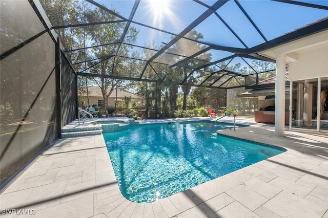 view of pool featuring glass enclosure, a pool with connected hot tub, and a patio