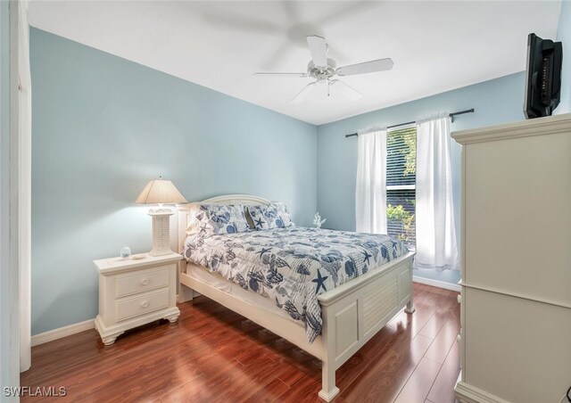 bedroom with a ceiling fan, baseboards, and dark wood-type flooring