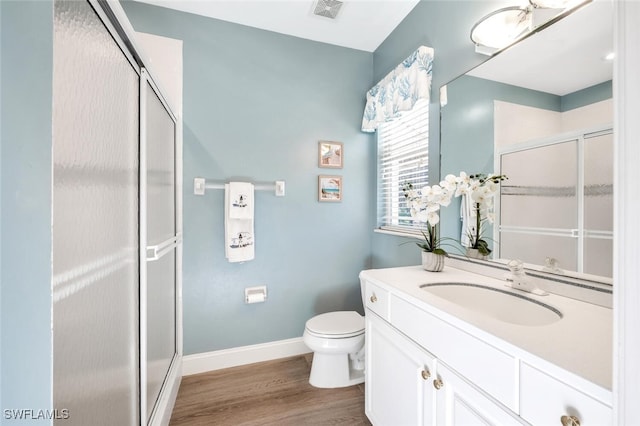 bathroom with a stall shower, baseboards, visible vents, wood finished floors, and vanity