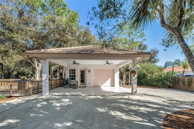 exterior space with stucco siding, concrete driveway, a ceiling fan, fence, and a garage