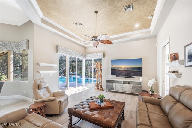 living room featuring ornamental molding, a raised ceiling, visible vents, and wood finished floors