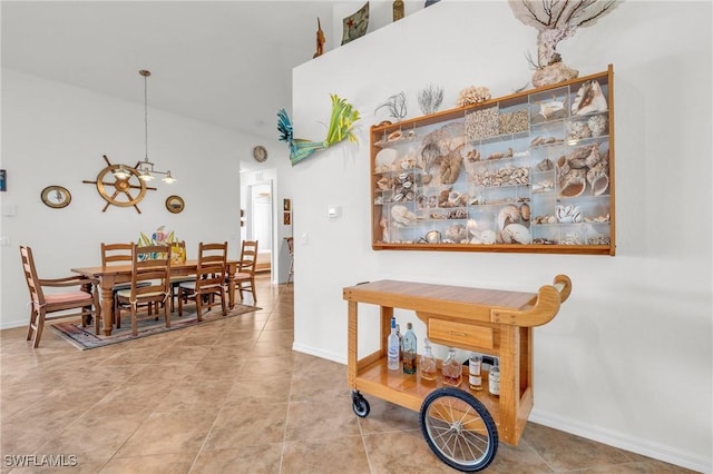 tiled dining area with a towering ceiling, baseboards, and an inviting chandelier