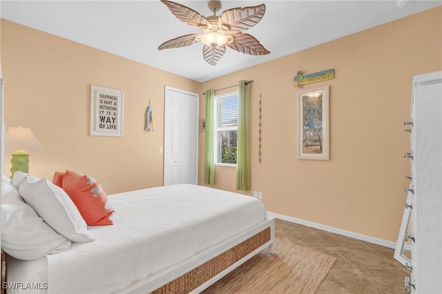 bedroom with a ceiling fan, a closet, baseboards, and light tile patterned floors