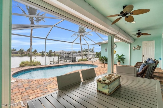 pool with glass enclosure, a water view, a patio, and ceiling fan