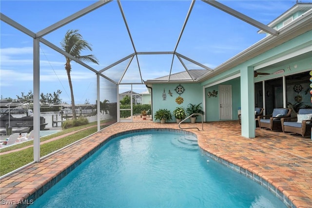 pool featuring a patio area, glass enclosure, and ceiling fan