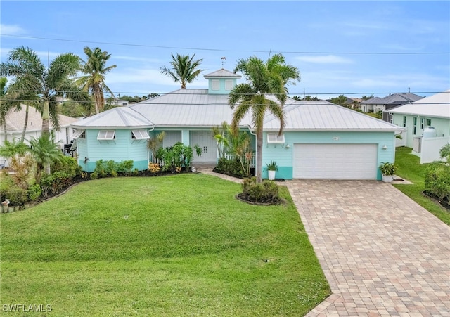 view of front of property with a garage, metal roof, decorative driveway, and a front yard