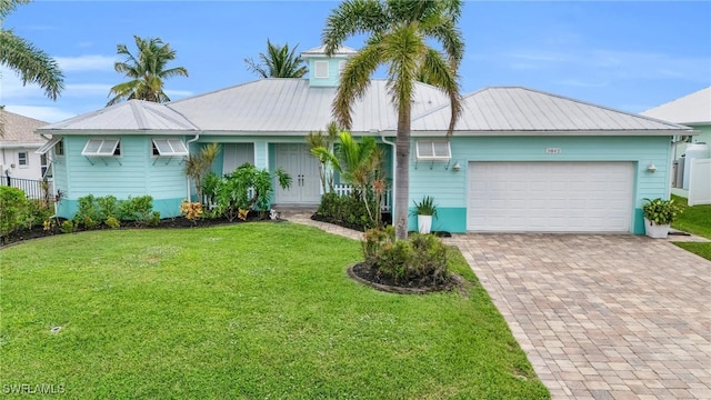 ranch-style house with a garage, metal roof, a front lawn, and decorative driveway