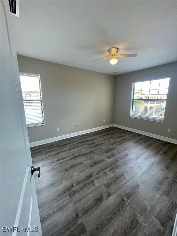 unfurnished room featuring dark hardwood / wood-style floors, ceiling fan, and a healthy amount of sunlight