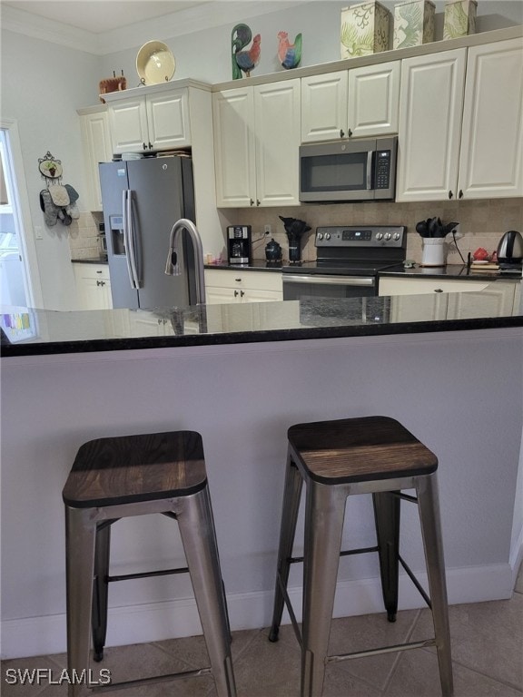 kitchen with a kitchen breakfast bar, sink, light tile patterned floors, ornamental molding, and appliances with stainless steel finishes