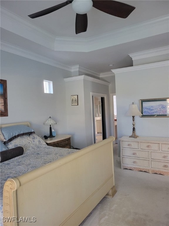 carpeted bedroom with a tray ceiling, ceiling fan, and crown molding