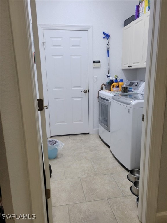 washroom with washing machine and clothes dryer and cabinets