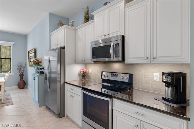 kitchen with appliances with stainless steel finishes, backsplash, white cabinetry, and light tile patterned flooring