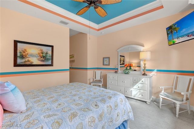 carpeted bedroom with a raised ceiling, ceiling fan, and crown molding