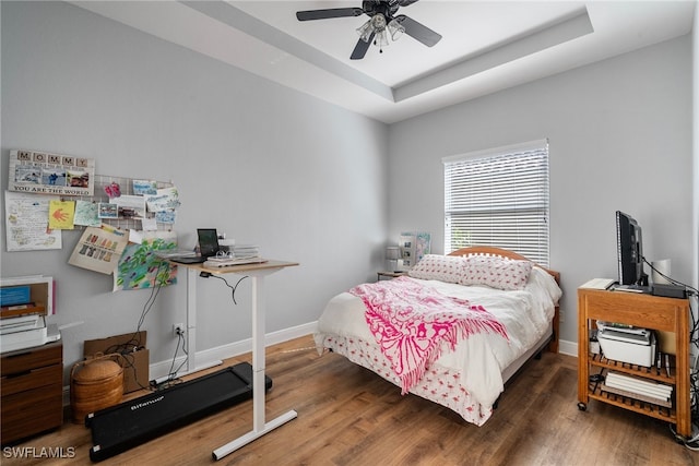 bedroom featuring a raised ceiling, baseboards, ceiling fan, and dark wood-style flooring