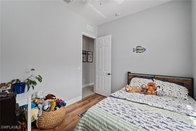 bedroom featuring ceiling fan, wood finished floors, visible vents, and baseboards