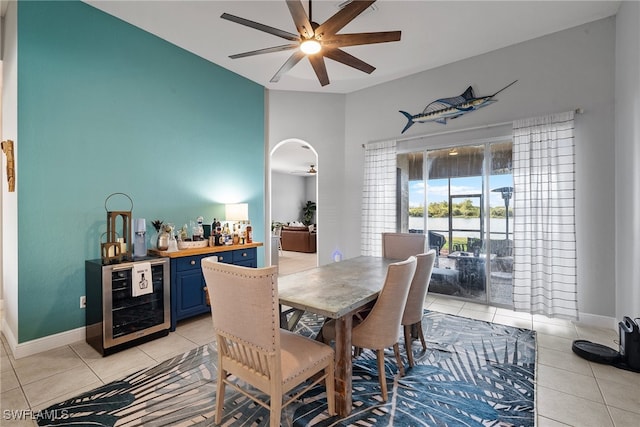 dining area with arched walkways, beverage cooler, light tile patterned flooring, and ceiling fan