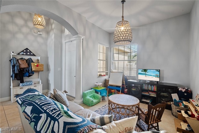 rec room with arched walkways, a notable chandelier, light tile patterned floors, ornate columns, and baseboards