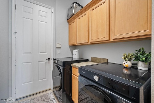 clothes washing area with cabinet space, washer and clothes dryer, and light tile patterned floors