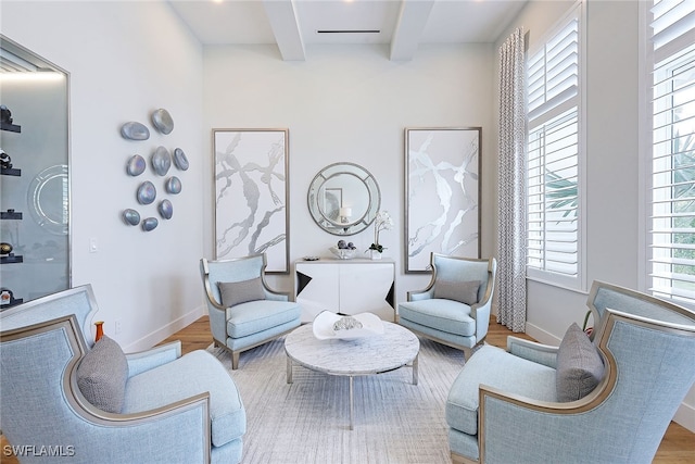 living area with beamed ceiling and light hardwood / wood-style flooring