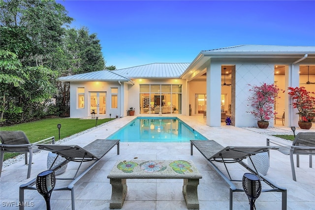 pool at dusk featuring a yard and a patio