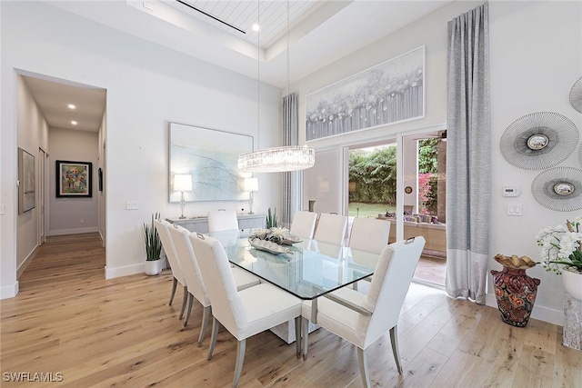 dining room with a high ceiling, light wood-type flooring, and a tray ceiling